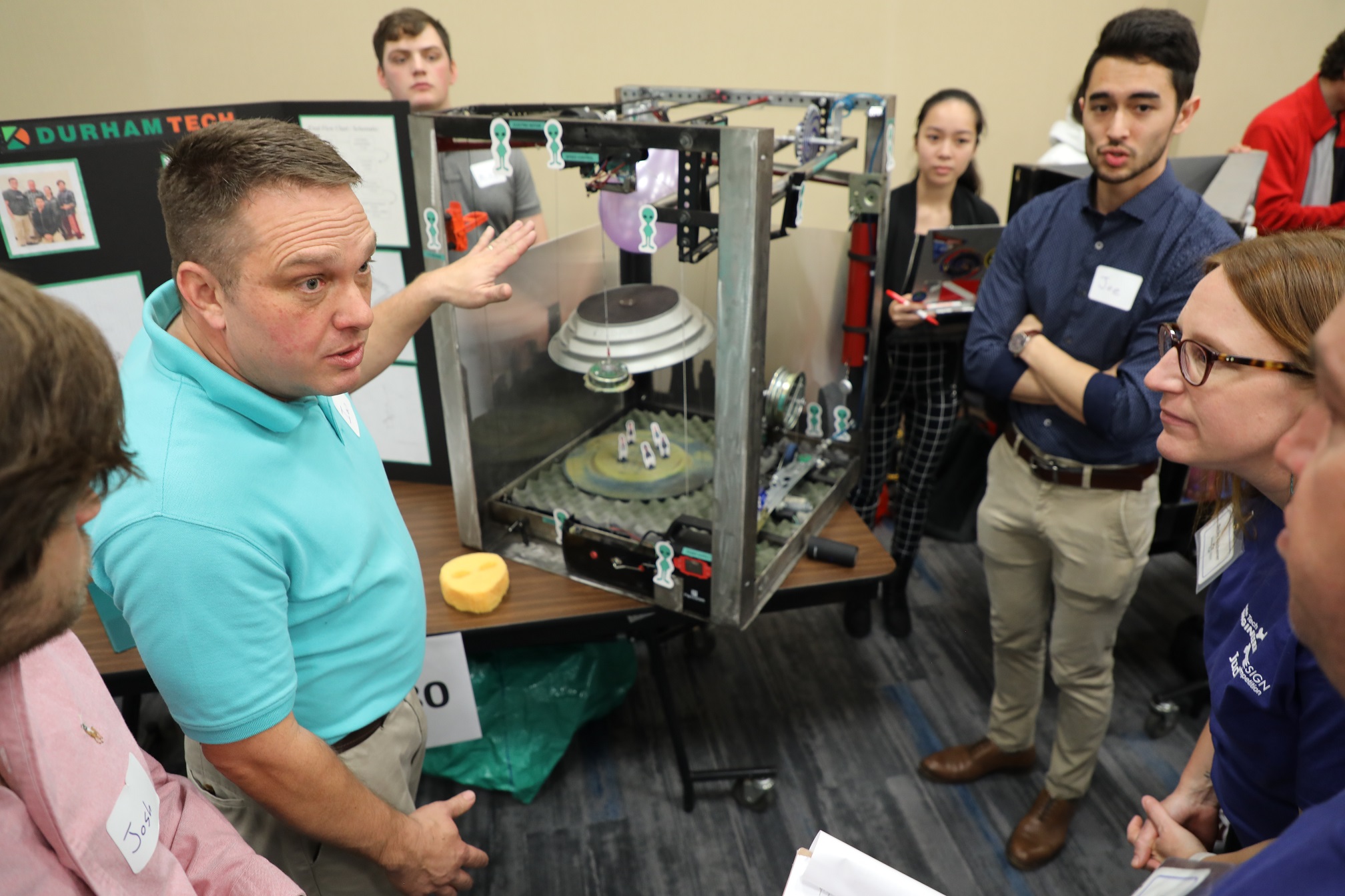 students standing next to their project and explaining to judges
