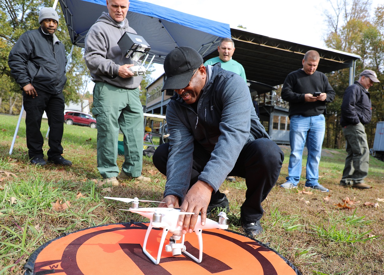 first responder squats on ground and touches drone