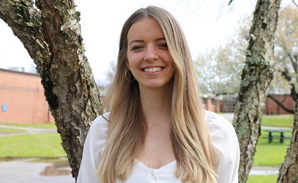 irina standing in front of tree on campus smiling