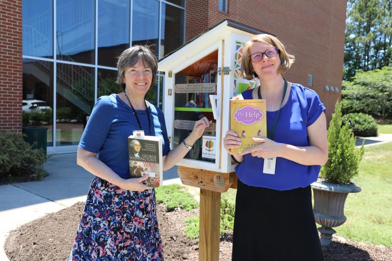 library staff with little free library on main campus 