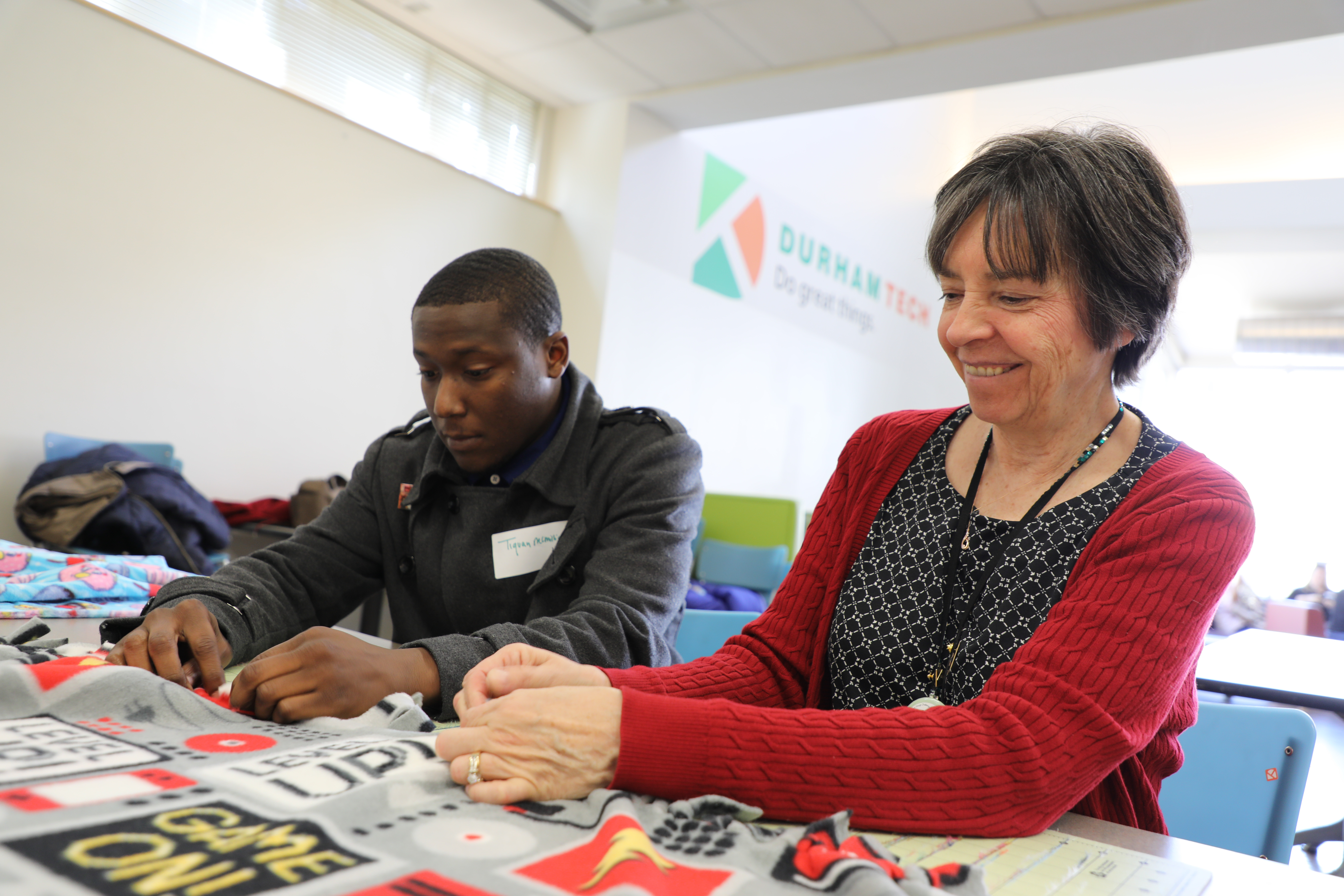 faculty member, student work on fleece blanket for MLK event 