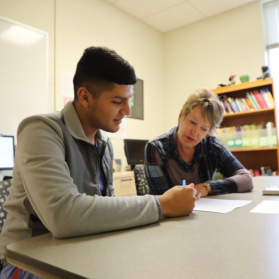 student and tutor sitting at table reading