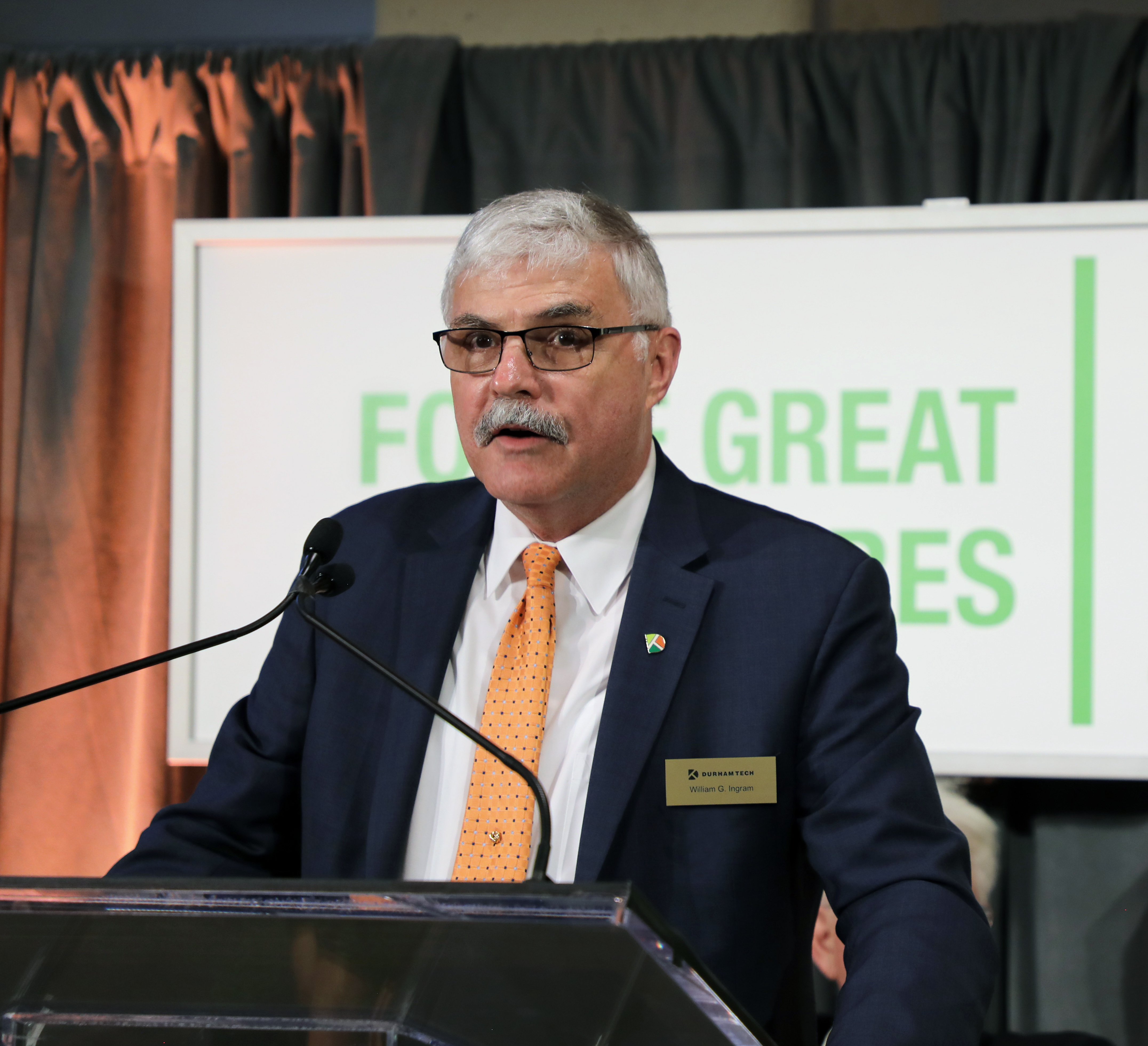 Dr. Ingram standing behind podium and in front of Forge Great Futures logo
