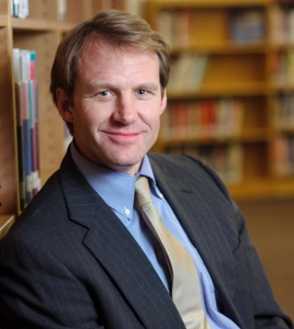 headshot of j.b. buxton in front of bookshelf
