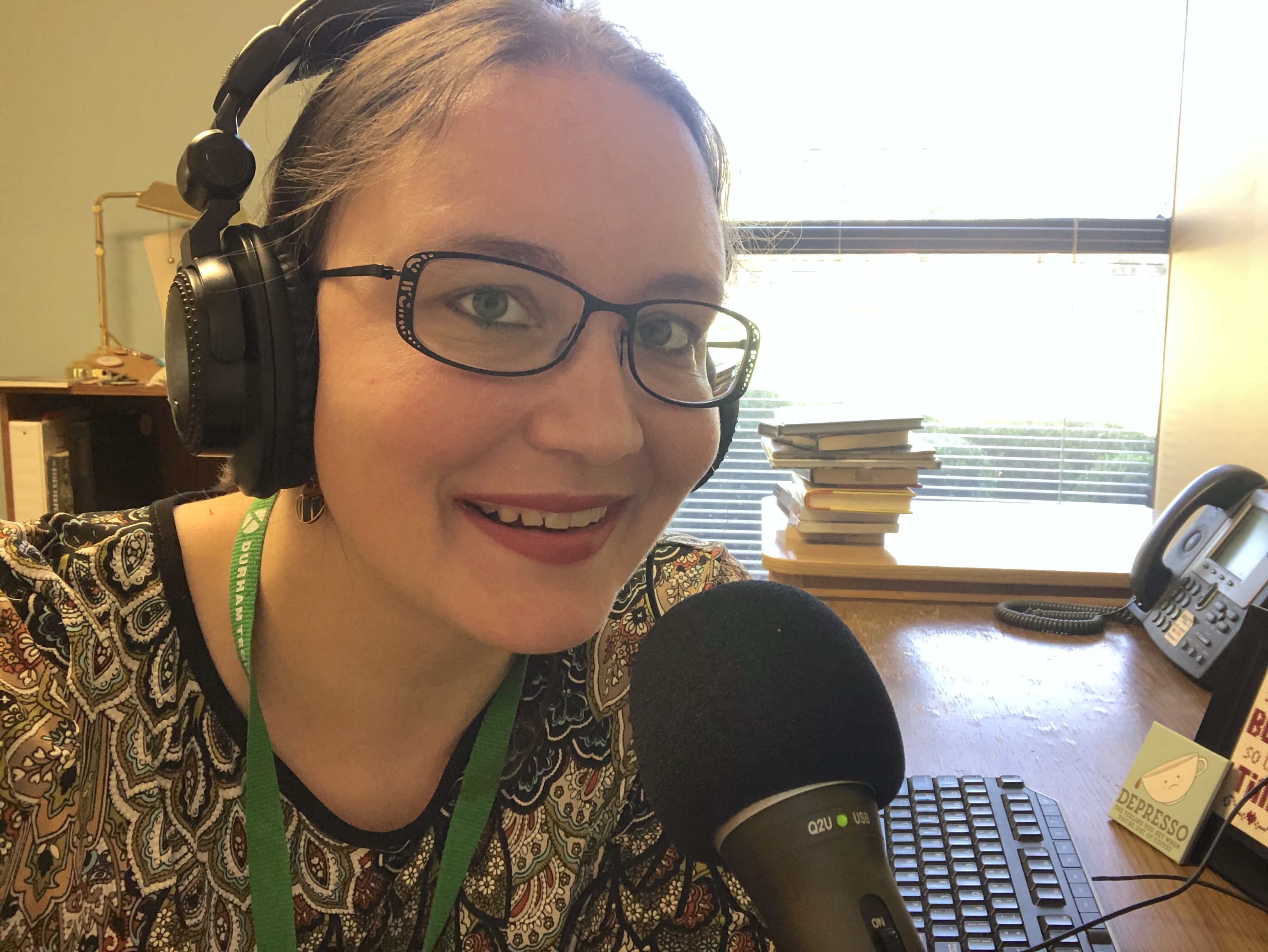 person with headphones on speaking into a microphone and smiling