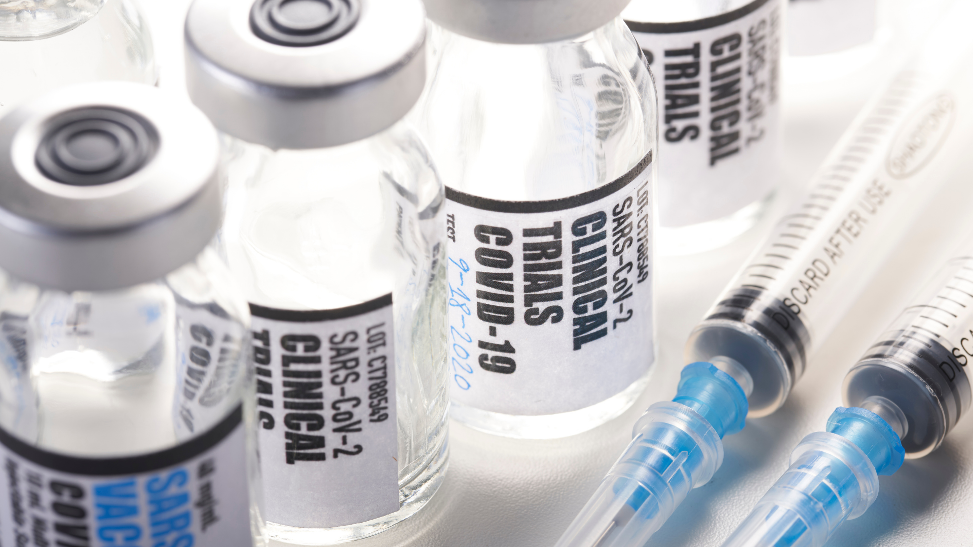 small glass bottles that say Clinical Trials and shots laying next to them 