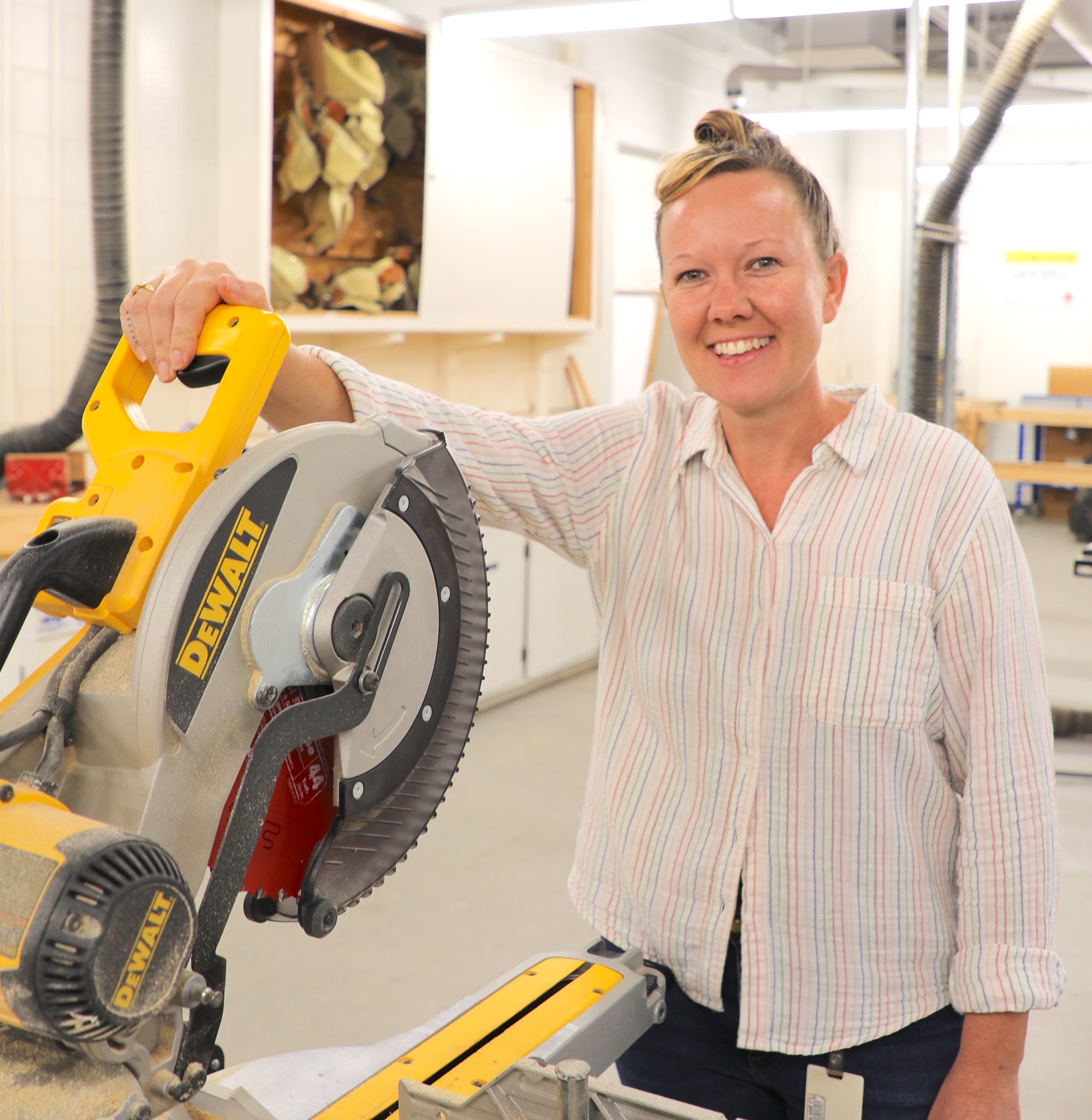 Maryah smiling at camera in front of table saw