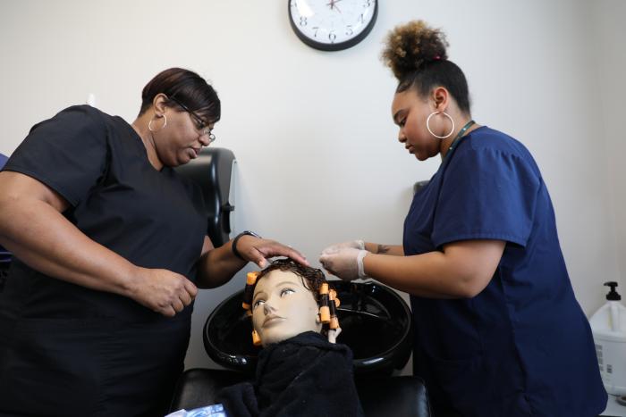 two people working on hair on mannequin