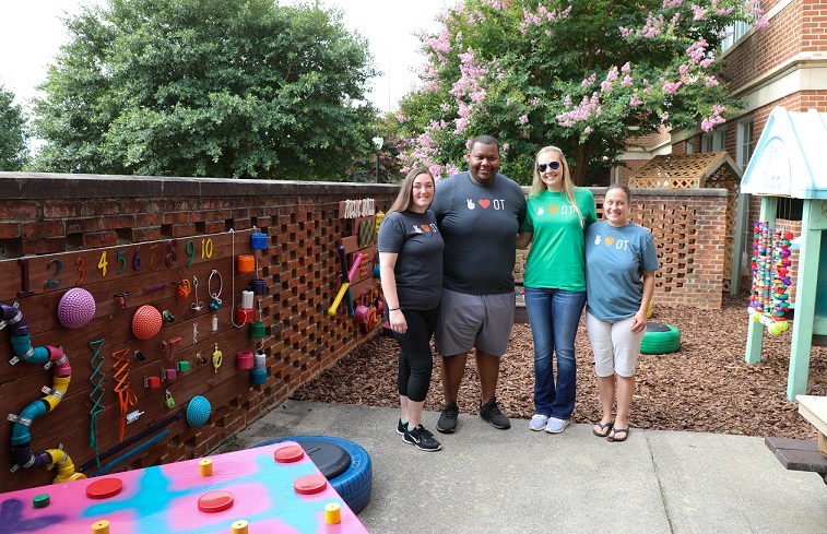 four students standing in play area smiling