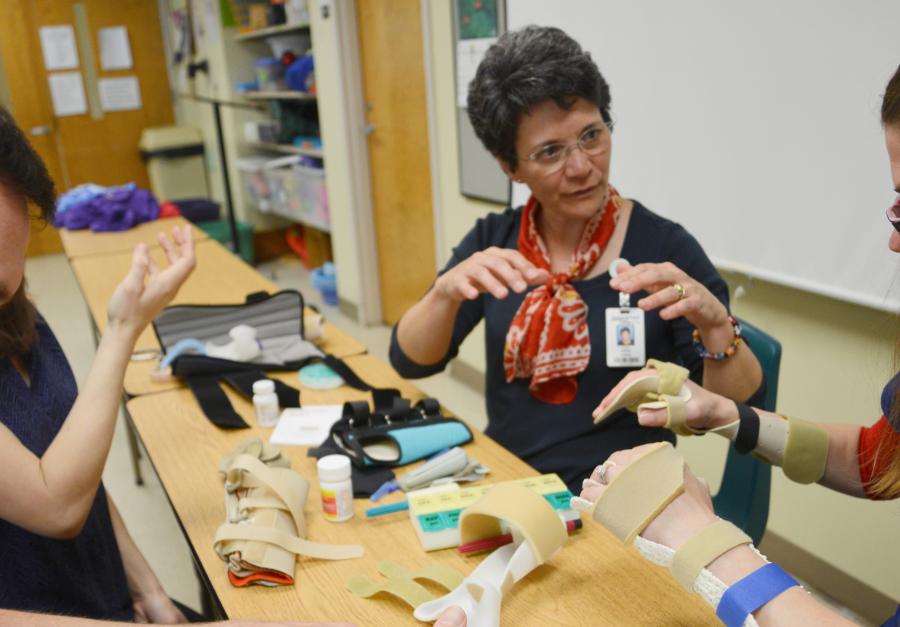 sue sitting at table talking to students about wrist support equipment