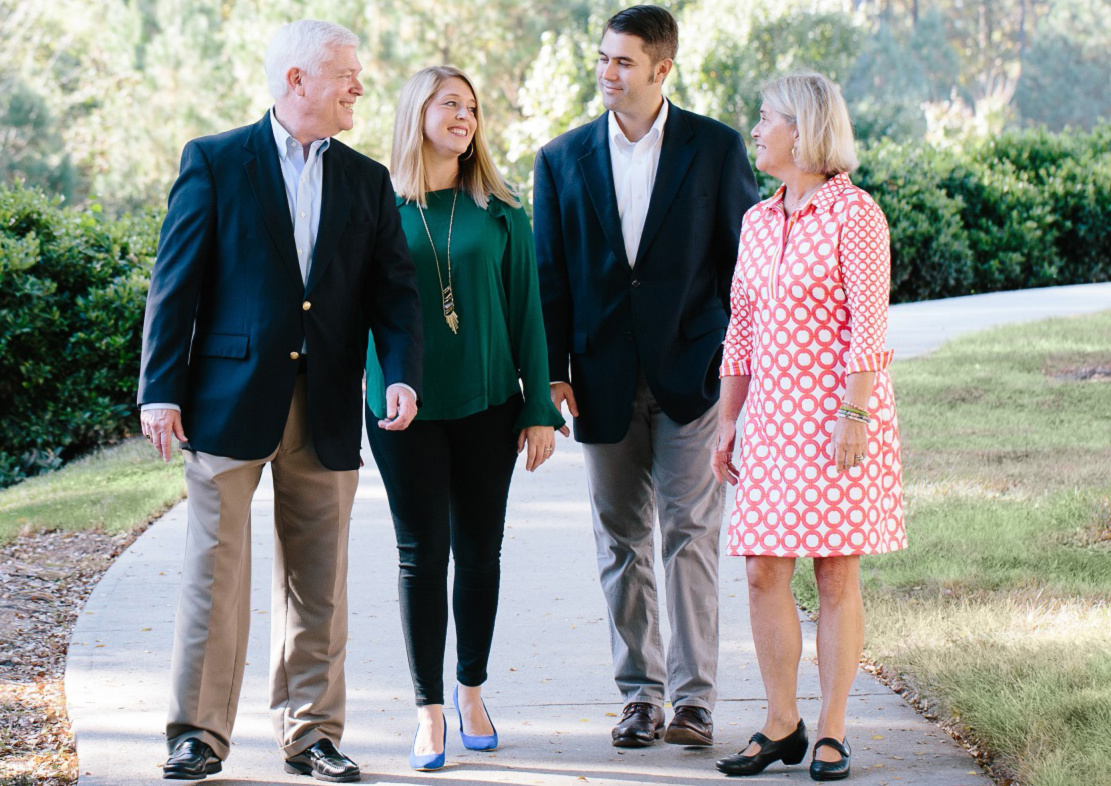 Griffin family walking down sidewalk smiling at each other on sunny day on main campus