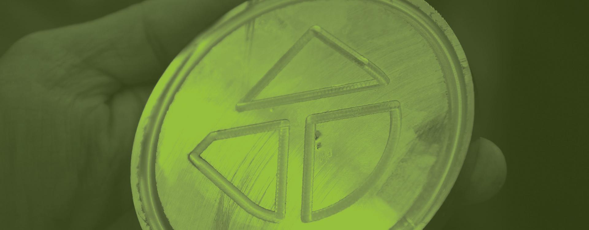 Round metal disc with Durham Tech icon engraved into it by Computer Integrated Machining program students