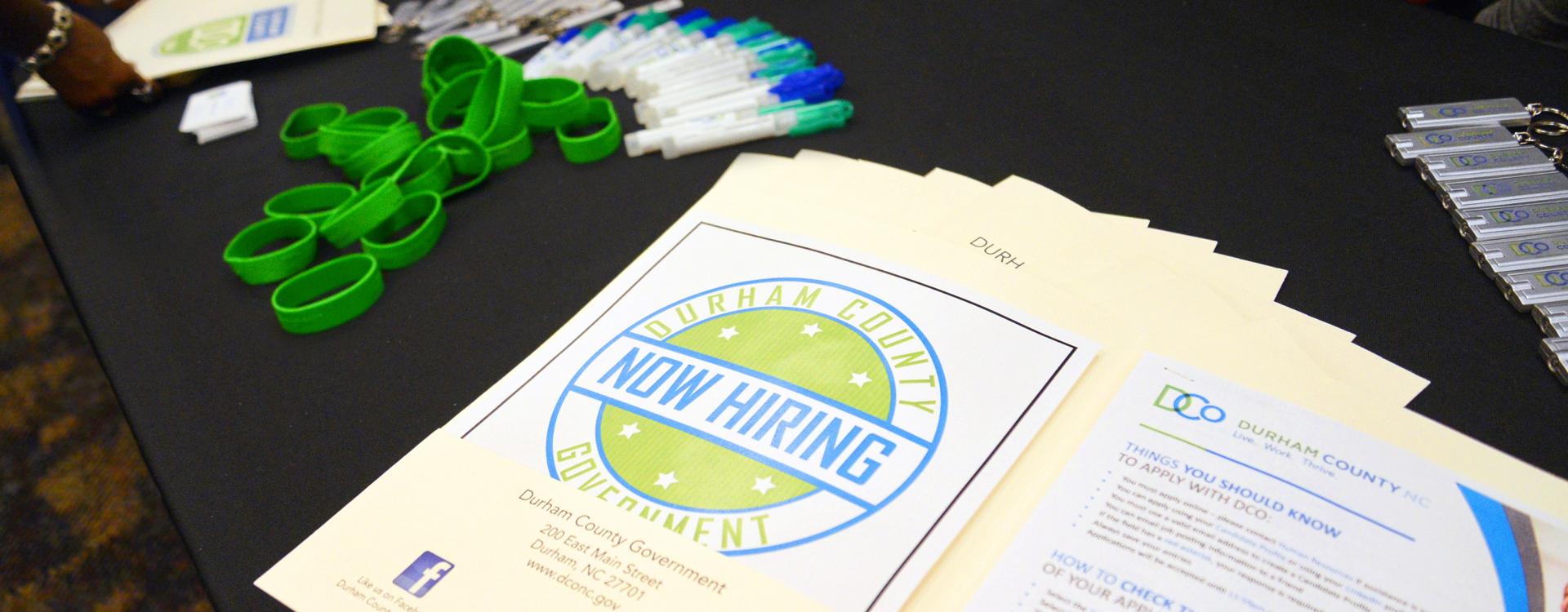 A photo of a recruitment table with promotional materials and branding giveaway items