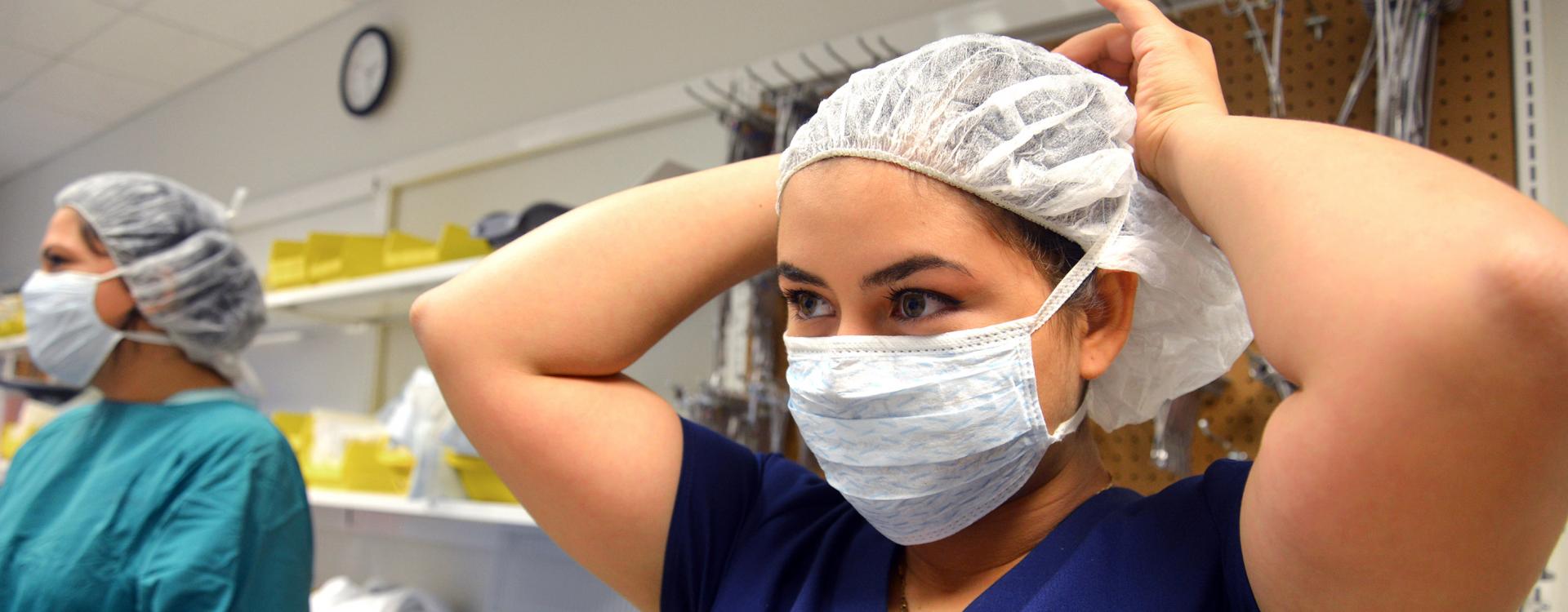 A Durham Tech student puts on a mask in a health technologies class