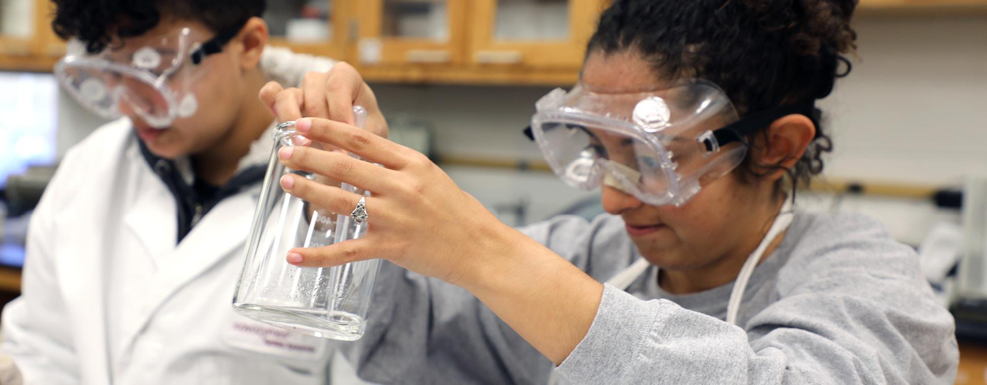 chemistry students work in lab mixing components in a beaker