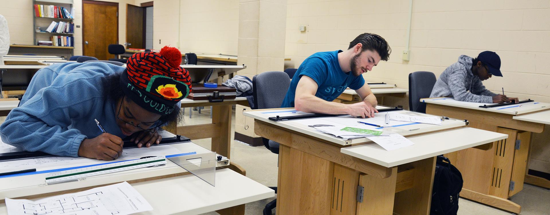 students practice drafting plans in class at drafting desks