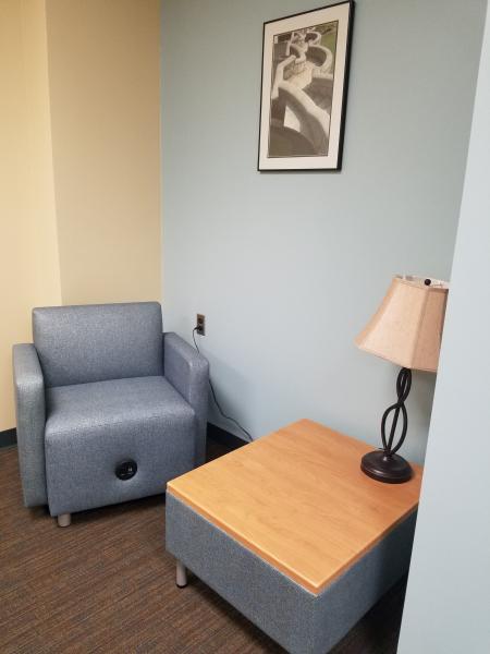 blue arm chair with charging port in base and low table with wood top and lamp