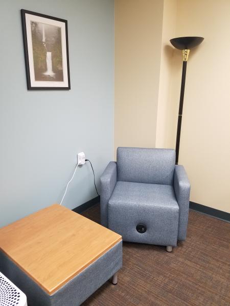 blue arm chair with charging port in base and low table with wood top and lamp and peek of air purifier