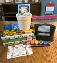 Paint your own pot (and plant your own flowers) Crafternoon kit, including ceramic pot, bag of planting soil, seed packet, paints and paintbrush. Also shown are four books on plants and gardening: How Plants Work, The Triumph of Seeds, The New American Homestead, and Gardening in the South. 