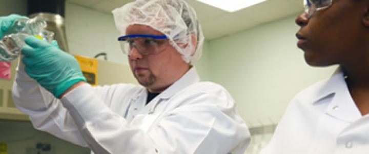 Biotechnology students working in protective gear under a hood