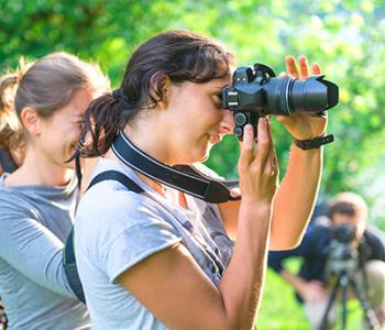 students using professional looking cameras to photograph something offscreen 