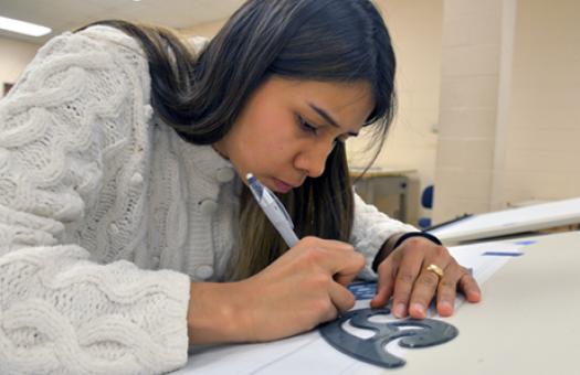 Female Architectural Technology student traces drafting outline in class.
