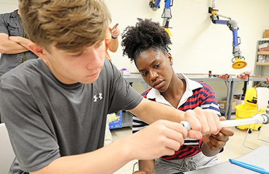 plumbing students work on readying a pipe for fitting