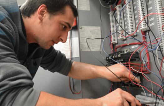 student screwing wires into an electrical board