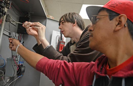 male students using tools on electrical system 
