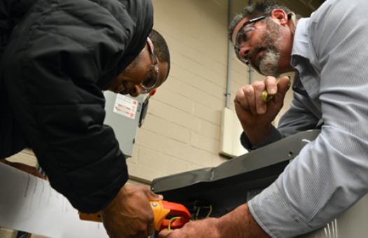 male teacher helps male student work on system 