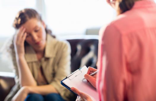 woman in chair records answers from despondent women on couch