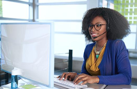 woman on computer with headphones on speaking with a customer