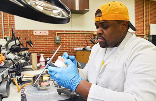 student in dental lab works on carving dentures