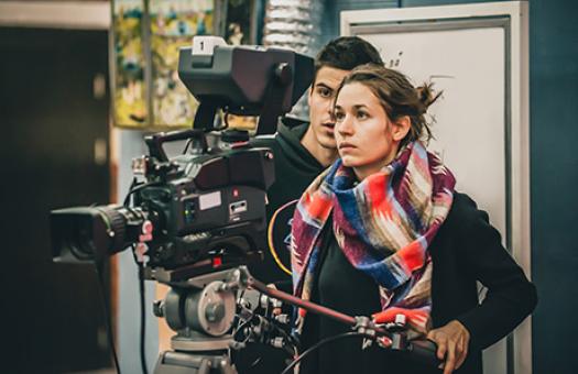 students standing behind a film camera