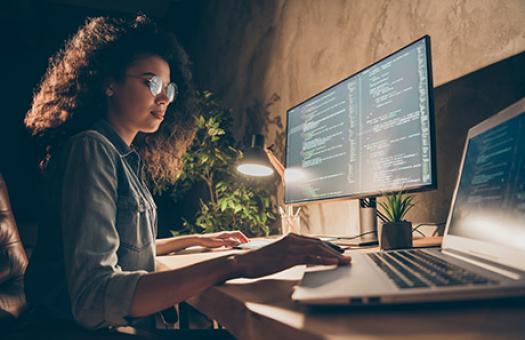 female student works on large computer monitor at home