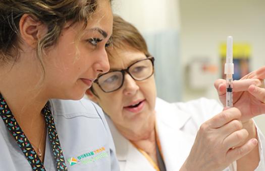 Instructor showing student how to flick a syringe to remove the air bubbles