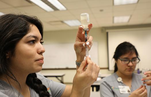 students practicing drawing a syringe from a medicine vial