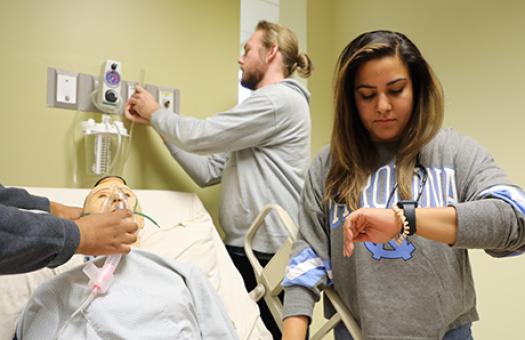 respiratory therapy students practice how to administer oxygen and take a patient pulse in lab