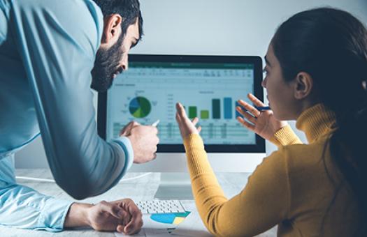 two students discuss charts and graphs depicted on computer screen
