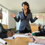 A business person stands in front of a group during a board meeting.