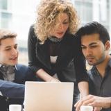 A group of business people look at a laptop.