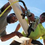 carpentry students use nail gun to secure wood brace