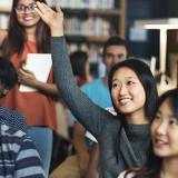 Diverse group of students raising their hand in a class