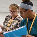 A male Durham Tech student points with a pen in his right hand to an EKG chart held by the EKG class instructor.