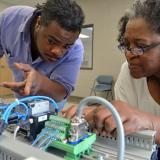 male student and female student observe controller in advanced manufacturing class 