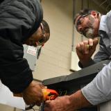male teacher helps male student work on system 