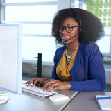 woman on computer with headphones on speaking with a customer