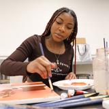 fine arts student works on a painting in class