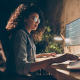 female student works on large computer monitor at home