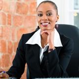 Female in a business suit sitting at a desk with a computer screen